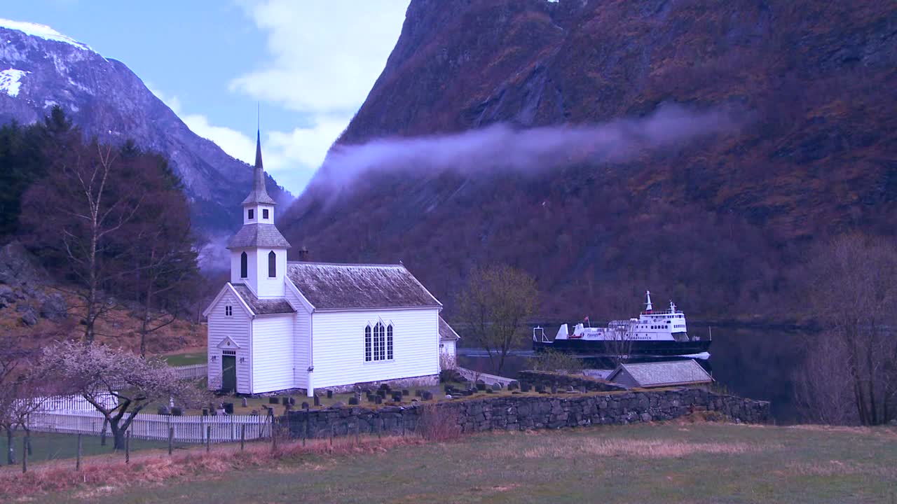 페리 보트는 노르웨이의 해안을 따라 예쁜 교회를 통과합니다.