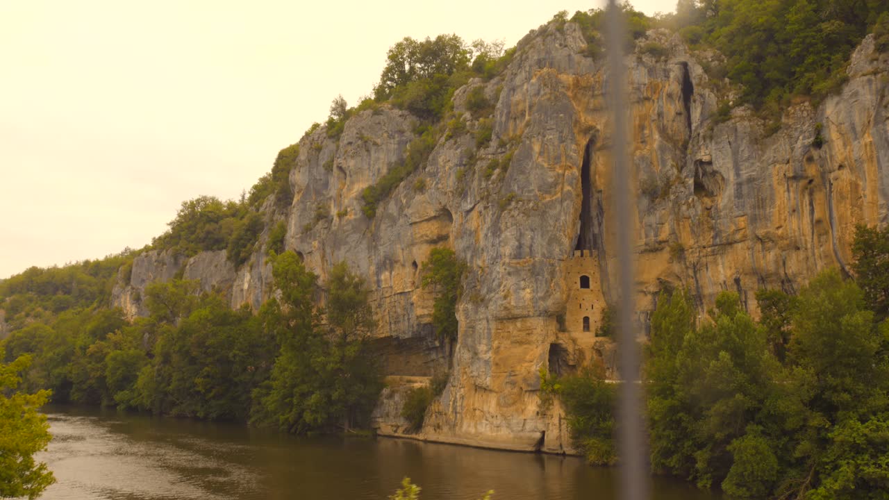 A view of the historic troglodyte dwellings carved into the majestic cliffs of Bouziès in the Quercy region of France, showcasing this unique and ancient site