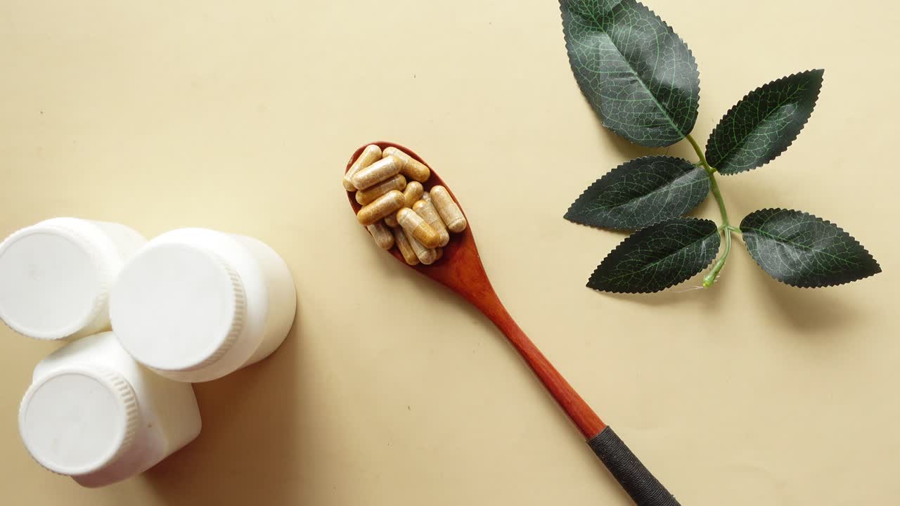 Herbal Pills in Wooden Spoon with Green Leaves