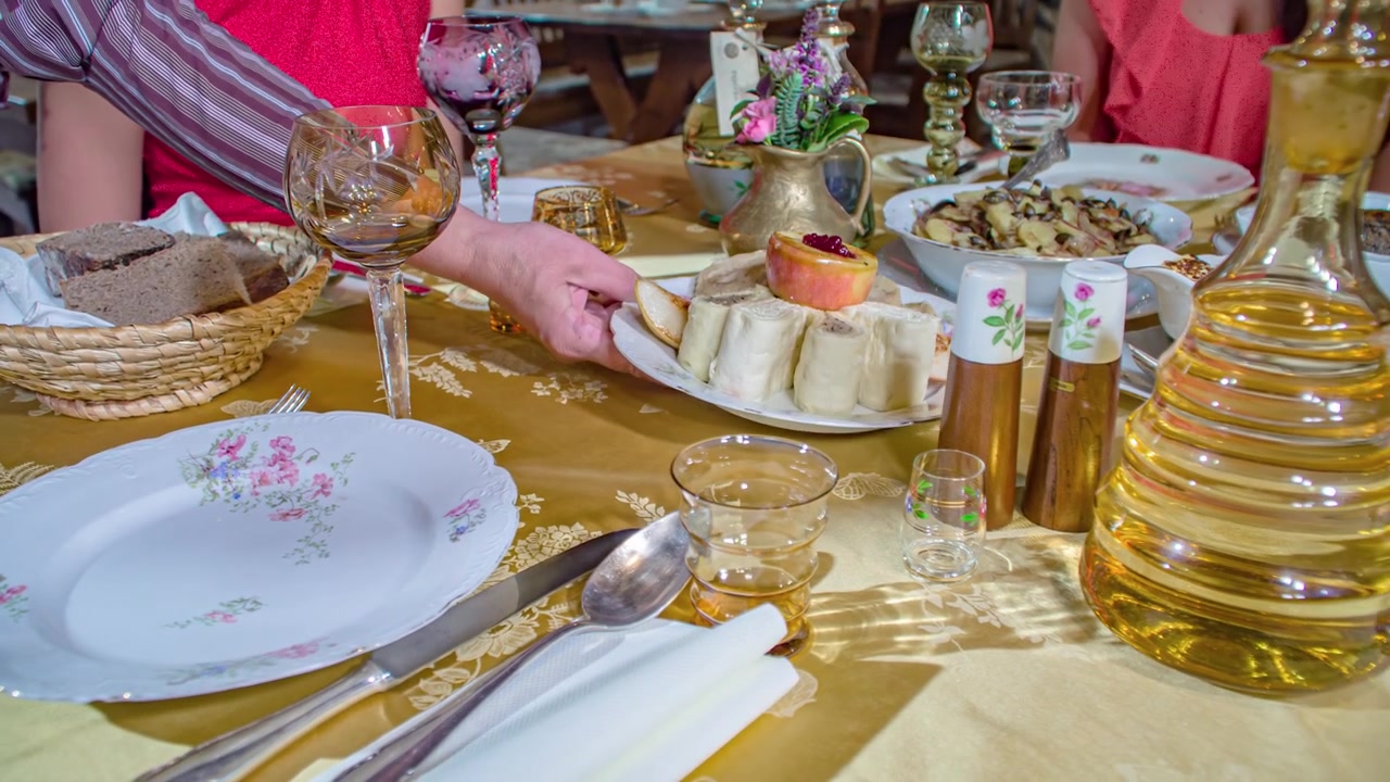 Tjener serverer salte osteknedler på et bord, traditionelt kaldet ønskebord i Slovenien. Nærbillede med fokus på hånden og måltidet.
