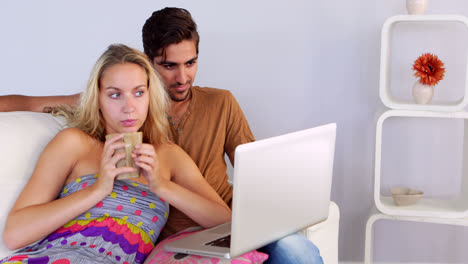 pareja aburrida viendo la computadora portátil en el sofá