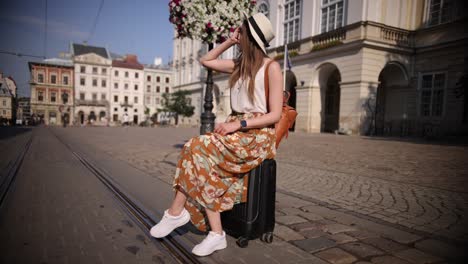 traveler woman sitting on a suitcase, dreaming adventures. concept of travel.