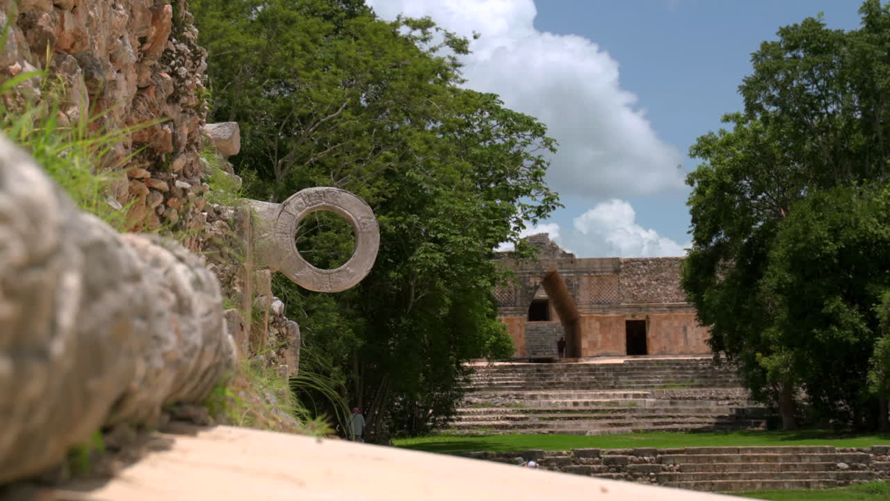 antigua cancha de pelota maya en uxmal, yucatán, rodeada de ruinas y vegetación tropical, poca profundidad del campo estableciendo artefacto deportivo