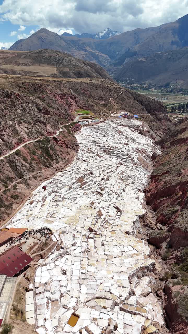 Wide flyover stunning patchwork of salt ponds at the salt mines of Maras in Peru, aerial vertical video