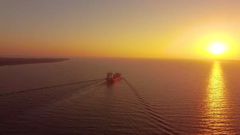 cargo ship sailing into the horizon during a yellow sunset or sunrise