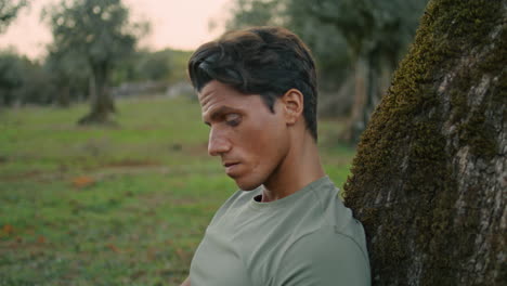 Serious-farmer-relaxing-nature-portrait.-Calm-man-posing-at-olive-tree-close-up