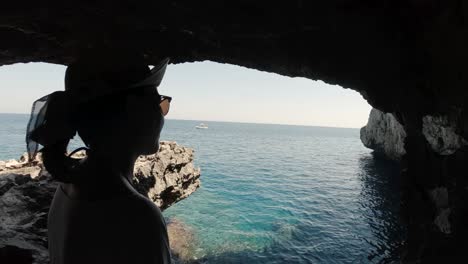 una niña mirando el mar desde el interior de una cueva marina cerca de paphos, cypris