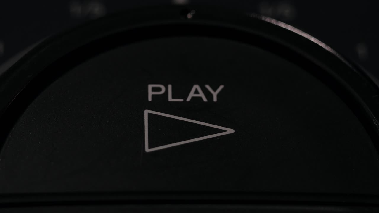 Finger presses circular play button with white triangle icon in dark setting