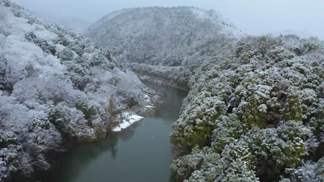 Snow-falling-over-Katsura-River,-Aerial-Push-Shot-in-Arashiyama-Kyoto