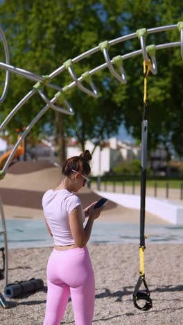 woman using phone at outdoor fitness park