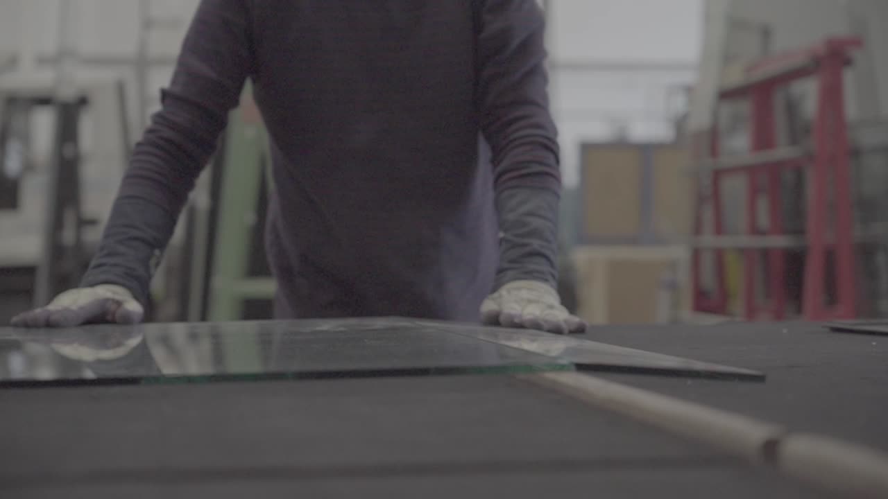 Machine operator using cutter for glass in workshop