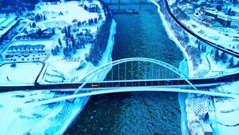 4k winter aerial birds view over walter dale modern tied arch bridge twist drift as amber full length school bus is midway crossing over north saskatchewan river reflecting off cracked icy water2-2