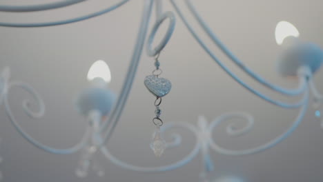 close-up of a white chandelier with delicate crystal and heart-shaped ornaments, emitting a soft glow