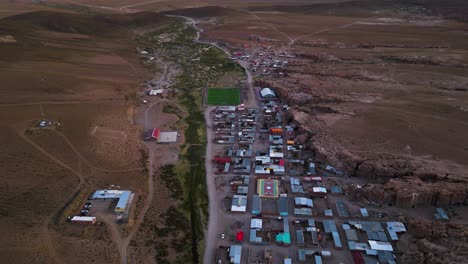 A-small-colorful-town-nestled-in-the-vast,-arid-landscape-of-chile-at-dusk,-aerial-view