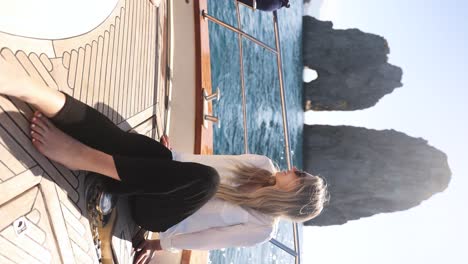 hermosa turista rubia explorando las rocas de farallones de capri en vacaciones en italia, vertical