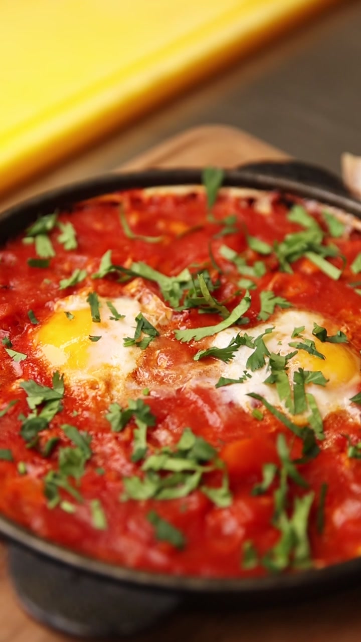 Appetizing Shakshuka Dish with Poached Eggs and Fresh Herbs