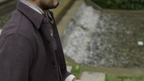 Middle-age-handsome-man-holding-glasses-in-his-hands,-sitting-in-the-park-by-the-water-alone,-thinking-and-contemplating-about-life