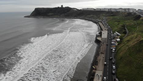 los surfistas reman para montar las olas en scarborough, yorkshire, reino unido