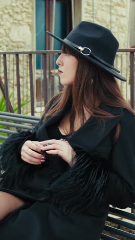 elegant woman in black coat sitting on a bench in her town and looking around