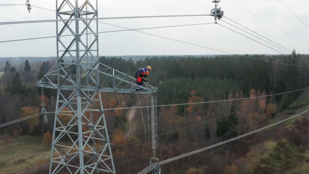 Engineer working high up on pylon, hoisting equipment up