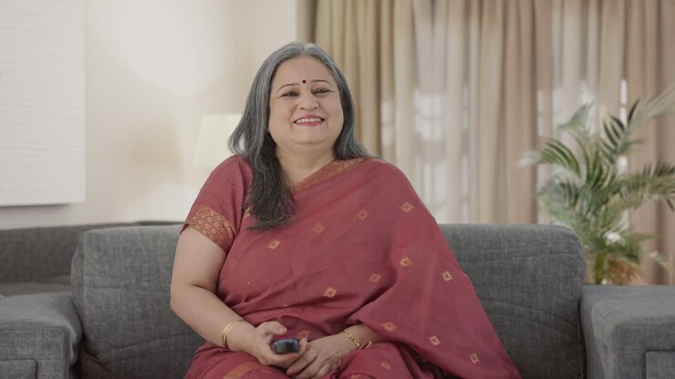 glückliche alte indische frau, die fernsieht und lacht