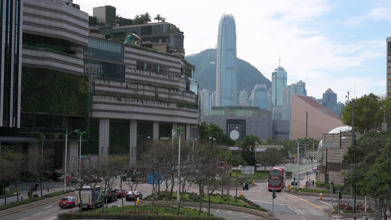 los vehículos conducen y viajan a lo largo de una carretera mientras los rascacielos y el distrito financiero de la isla de hong kong se ven al fondo