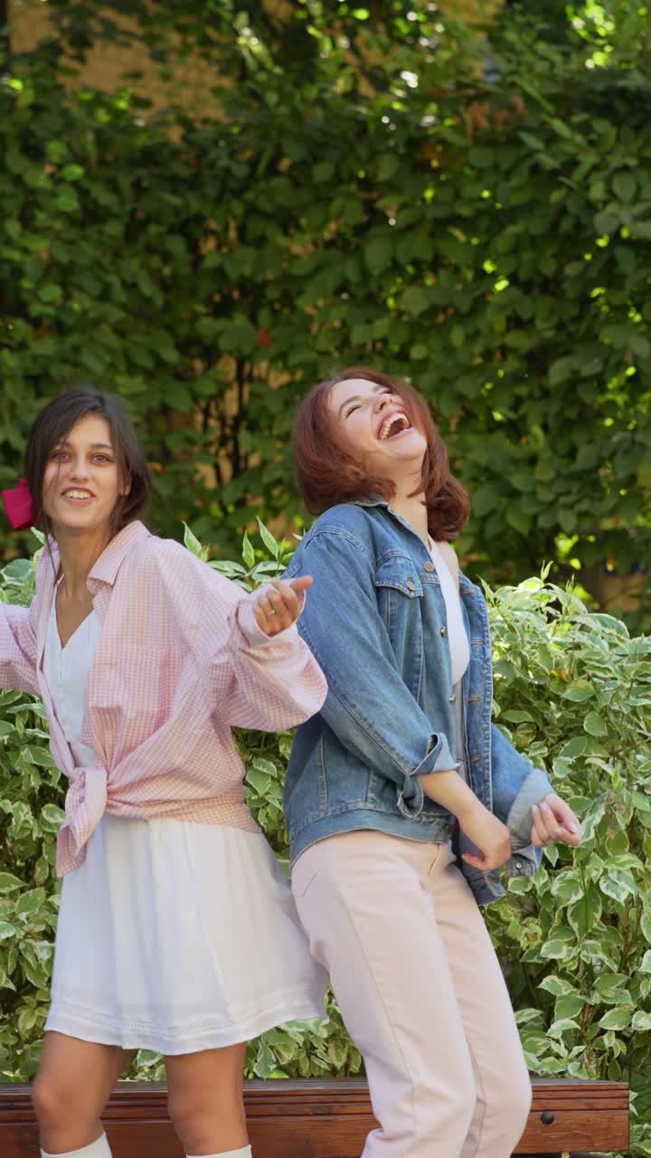 두 명의 젊은 여성이 공원에서 춤을 추고 웃고 있습니다.