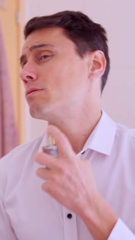 elegant man applying perfume in bathroom mirror