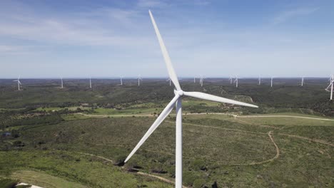 Aerial-closeup-of-single-windmill-with-many-windmills-behind-in-Portugal