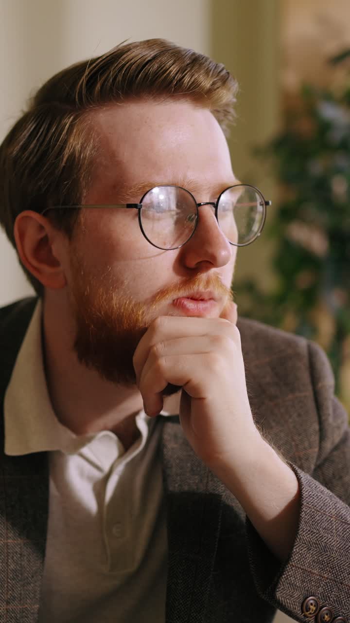 Thoughtful Man with Glasses Concentrating on Laptop