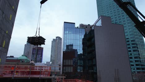 boom crane lifting material to a urban construction in middle of high-rise in ny - aerial view