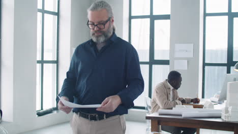 experienced male and female architects discussing document in office