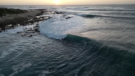 surfista montando olas en el crepúsculo, australia occidental