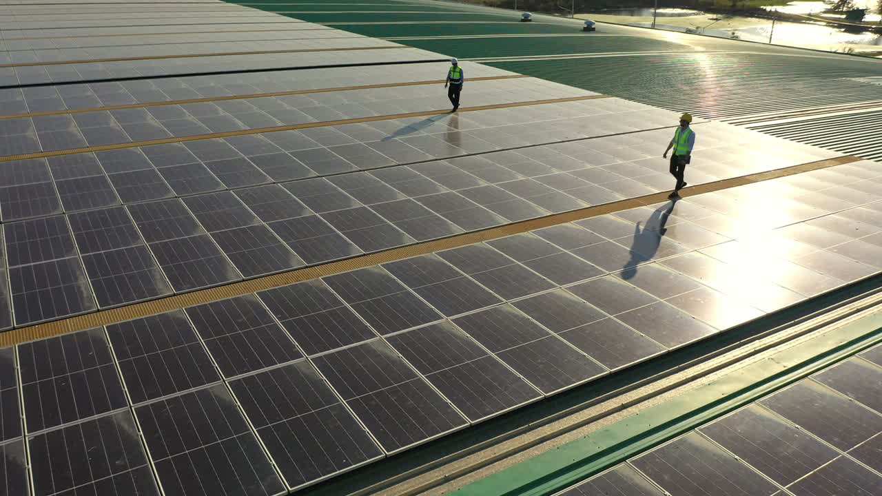 디지털 태블릿을 사용하는 4k 전문 엔지니어가 건물 지붕에서 태양전지 패널을 함께 유지합니다.