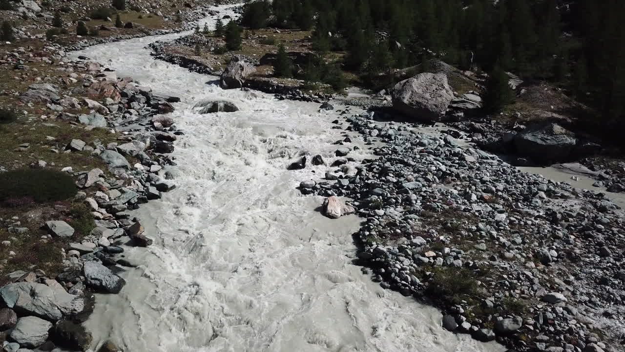vista aérea de drones de un río fangoso con fuerte corriente, valle rocoso en los alpes suizos, agua del glaciar, calentamiento global