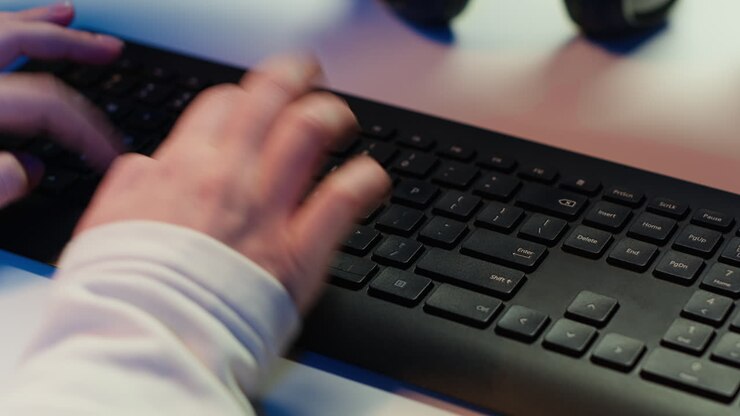 Specialista IT che digita sulla tastiera del PC, primo piano