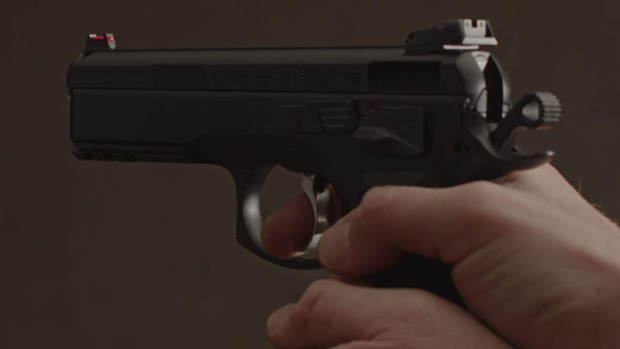 pulgar tirando hacia atrás el martillo de la pistola y disparando - cerrar