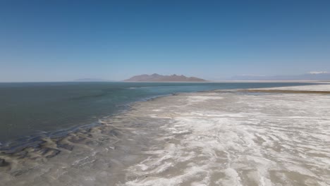 a 4k drone shot over the perfectly flat bonneville salt flats, found west of the great salt lake, in western utah, with a shallow layer of standing water flooding the vast salt plain’s surface