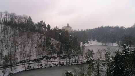 Aerial-view-of-frozen-lake-and-fairy-tale-castle-in-the-distance-at-winter