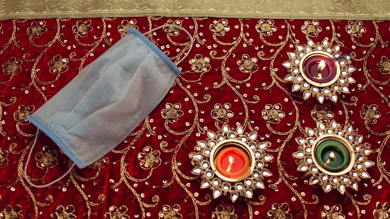 2020-diwali diyasflames van de la mano con las máscaras faciales