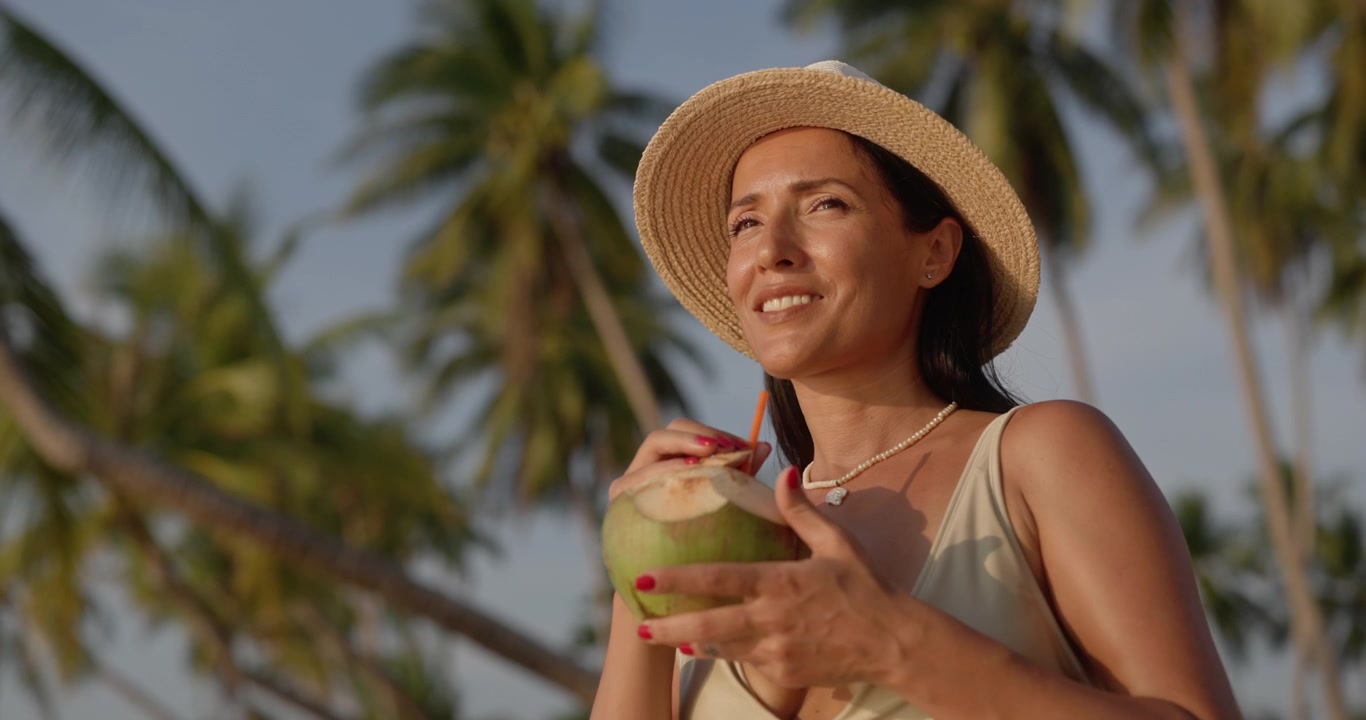 Young Woman Drinking Fresh Coconut on Tropical Beach at Sunset