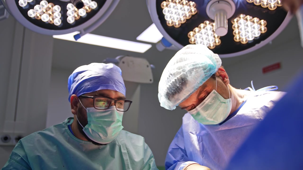Due chirurghi che collaborano lavorano a un intervento chirurgico per trauma sotto le grandi lampade rotonde. I medici eseguono la procedura in una moderna sala operatoria.