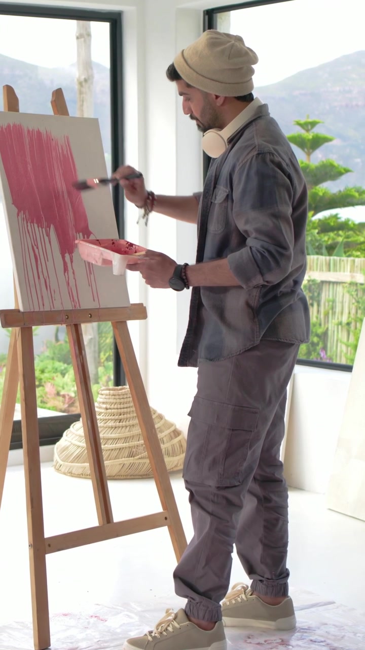 Video verticale: Intingendo il pennello, artista indiano che dipinge gocce rosa per riempire la tela a casa, spazio per il testo