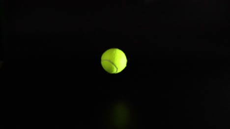 a tennis ball bounces on a dark surface