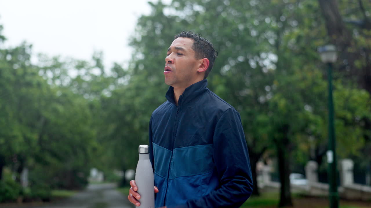 비가 오는 밖에서 물을 마시는 남자