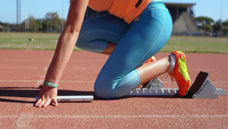 side view of female athlete taking starting position on a running track 4k