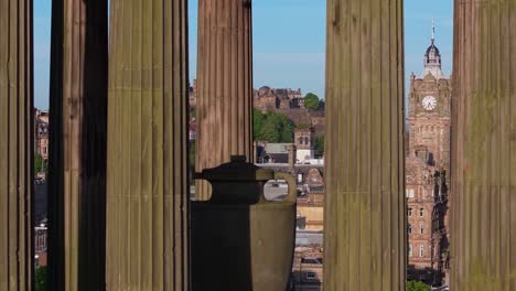 drone footage reveals edinburgh castle framed perfectly through the elegant columns of the dugald stewart monument, blending historic architecture and stunning views