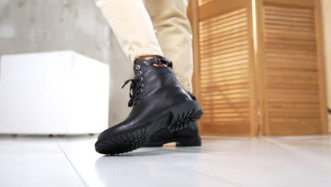 woman wearing black lace-up boots and beige pants