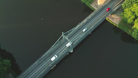 disparo de arriba hacia abajo de los coches que conducen en el puente de acero sobre el río