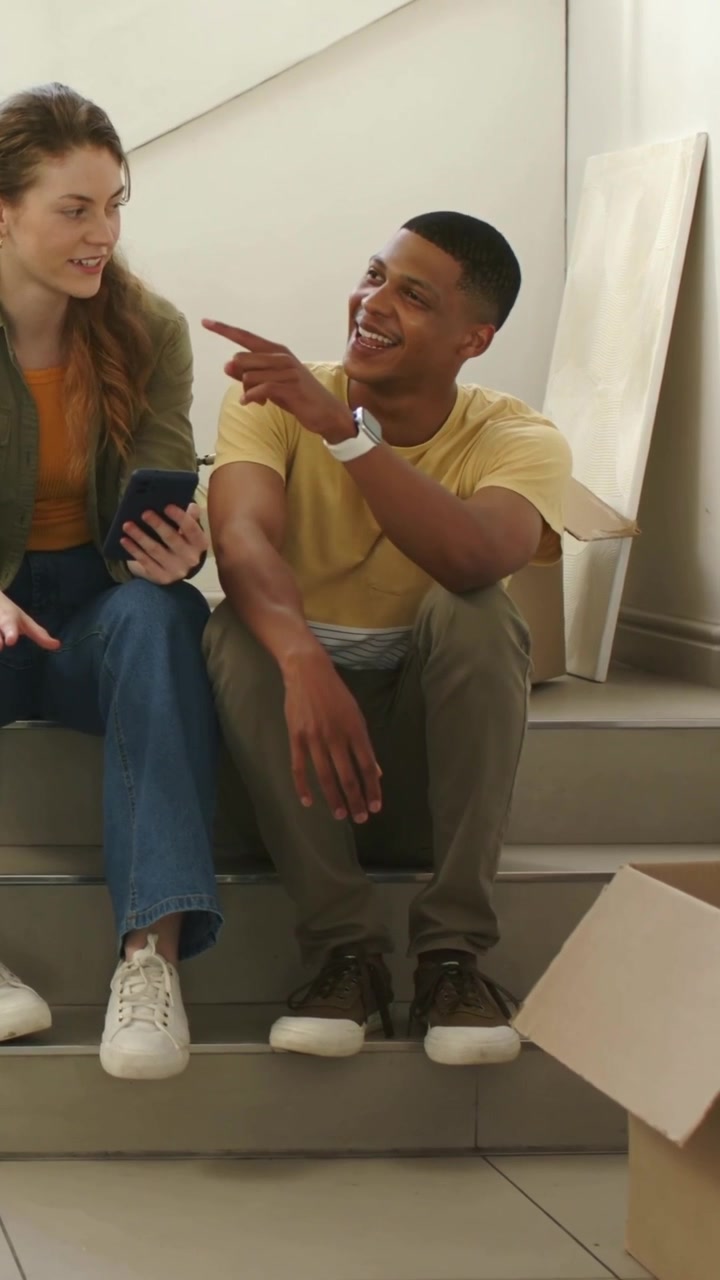 Vertical video: Turning, man yellow shirt pointing while woman scrolling phone on steps during move